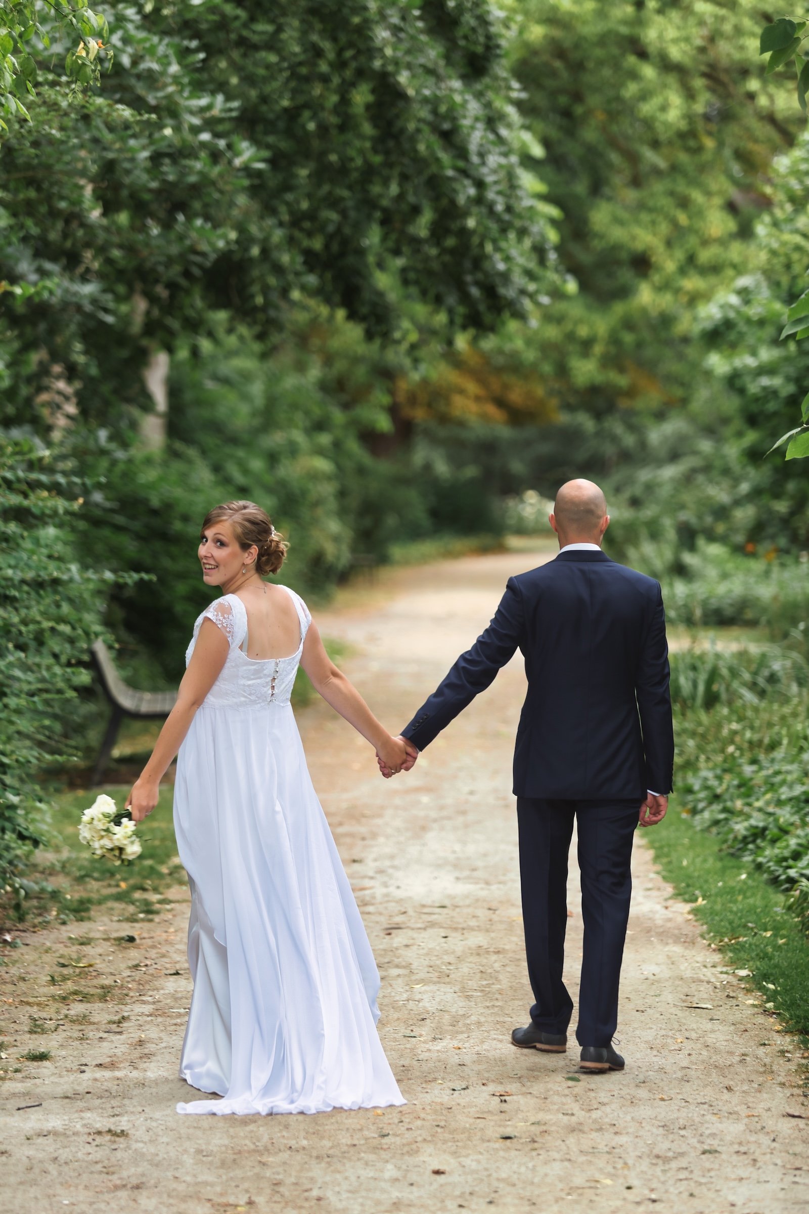 Huwelijk in Mechelen city wedding vastleggen van een micro huwelijk bruid in witte jurk en bruidegom in blauw kostuum tijdens love shoot holding hands